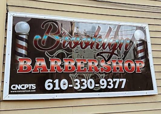 The Brooklyn Barbershop sign on the building, with the phone number 610-330-9377